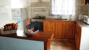 Uma cozinha com armários de madeira, fogão a gás, pia e micro-ondas.
