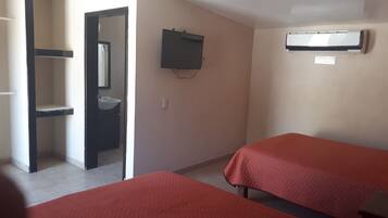 A room with two beds, a sink, a mirror, and an air conditioning unit.