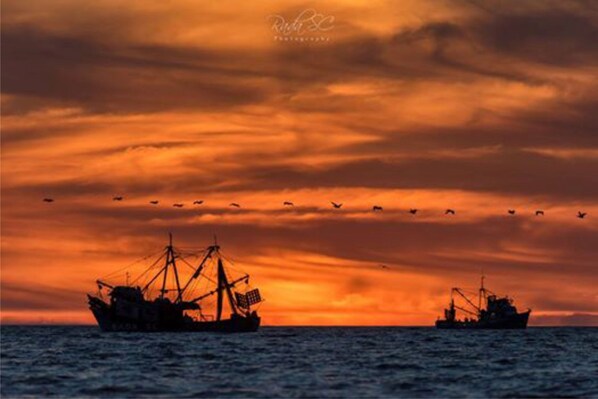 Two fishing boats silhouetted against a sunset sky.