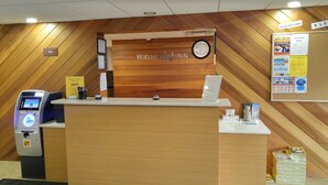 Mostrador de recepción del Wabaska Inn con un cajero automático, un reloj y carteles informativos.