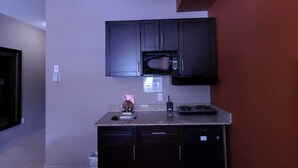 Una cocina compacta con armarios oscuros, un microondas y un lavamanos.