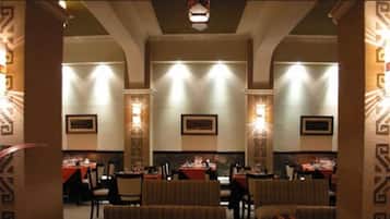 Un restaurant amb sostres alts, aplics decoratius murals i quadres enmarcats a les parets.