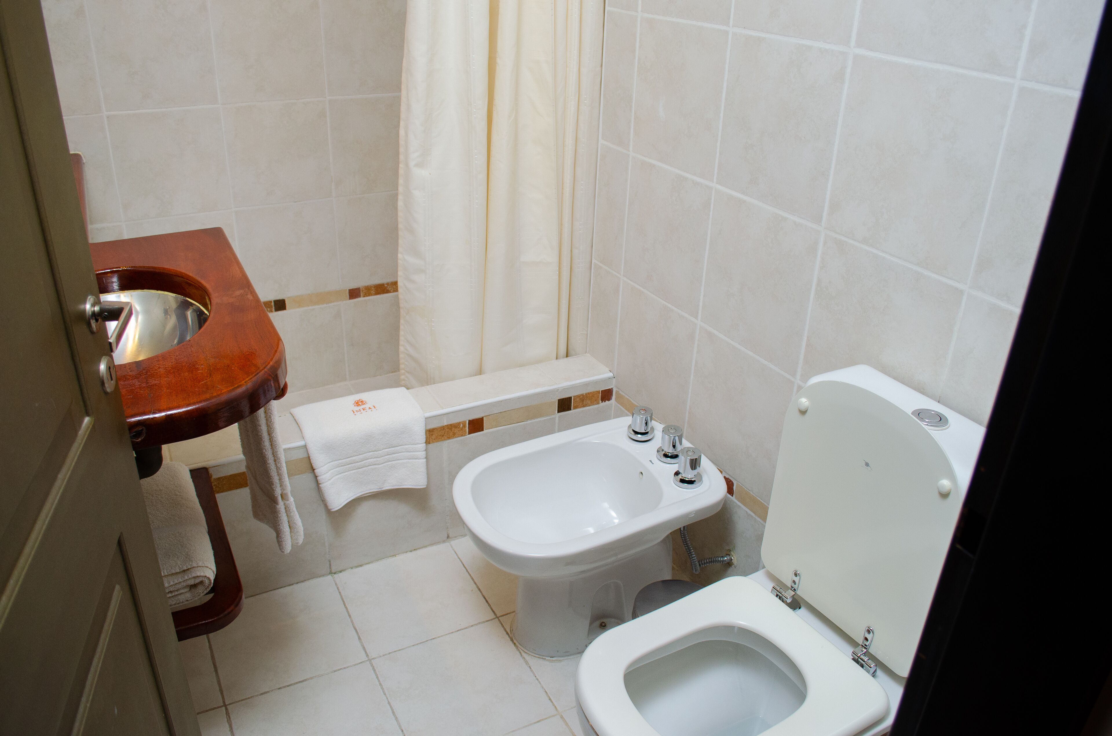 Et badeværelse med en trækommode, en bidet og et toilet.
