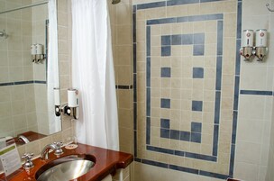 Un baño con lavamanos, espejo, cortina de ducha y paredes de azulejos.