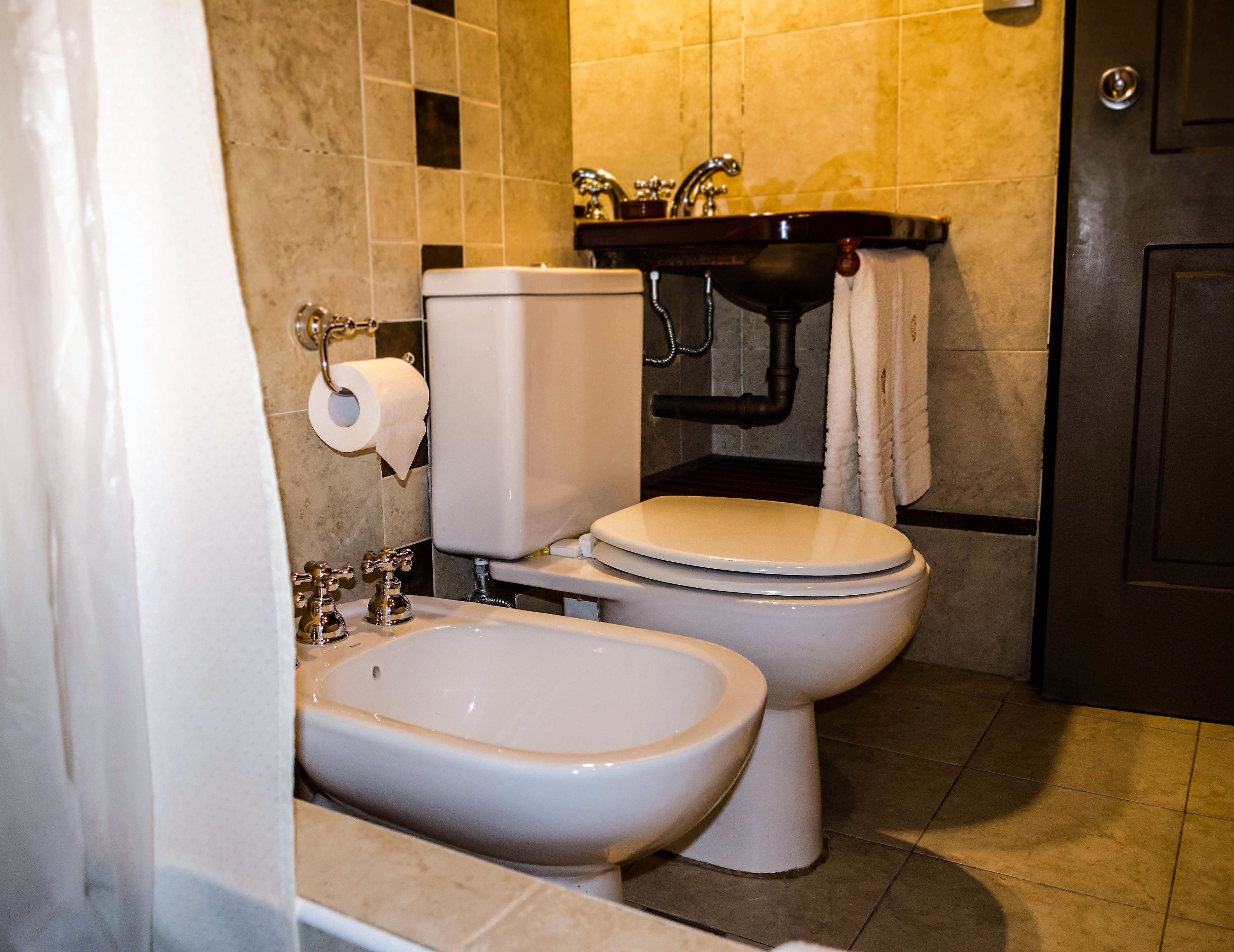 A bathroom with a toilet, bidet, sink, and towel rack.