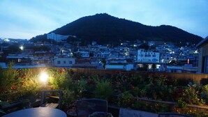 Un patio en la azotea con vista a un paisaje urbano y una colina al fondo.