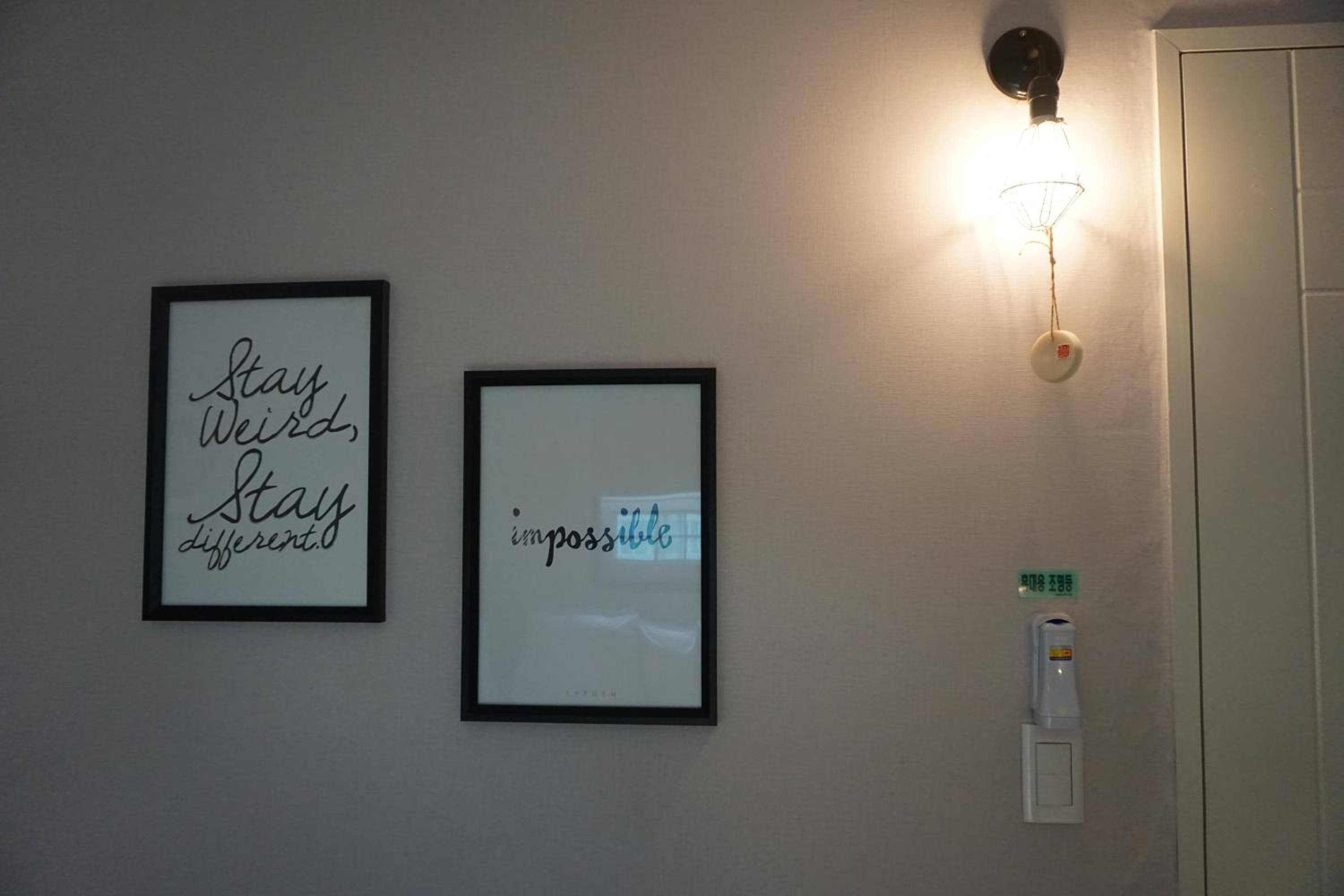 Dos marcos con citas inspiradoras en una pared, un aplique y una puerta con lector de tarjetas.