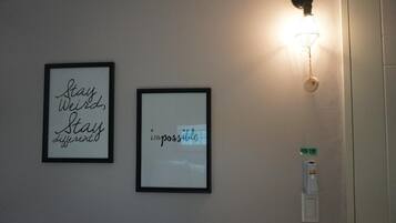 Dos marcos con citas inspiradoras en una pared, un aplique y una puerta con lector de tarjetas.
