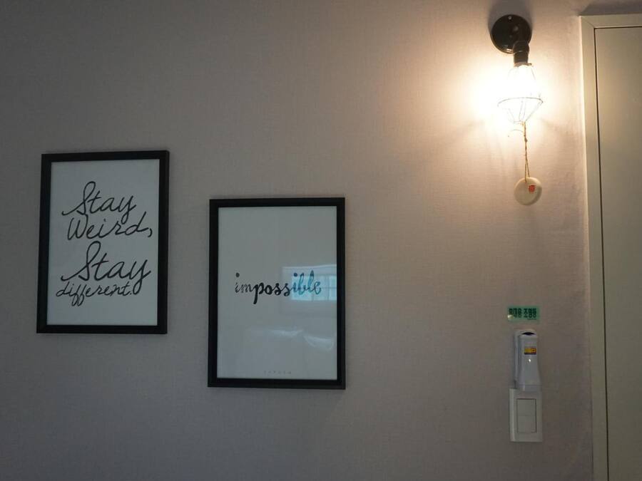Dos marcos con citas inspiradoras en una pared, un aplique y una puerta con lector de tarjetas.
