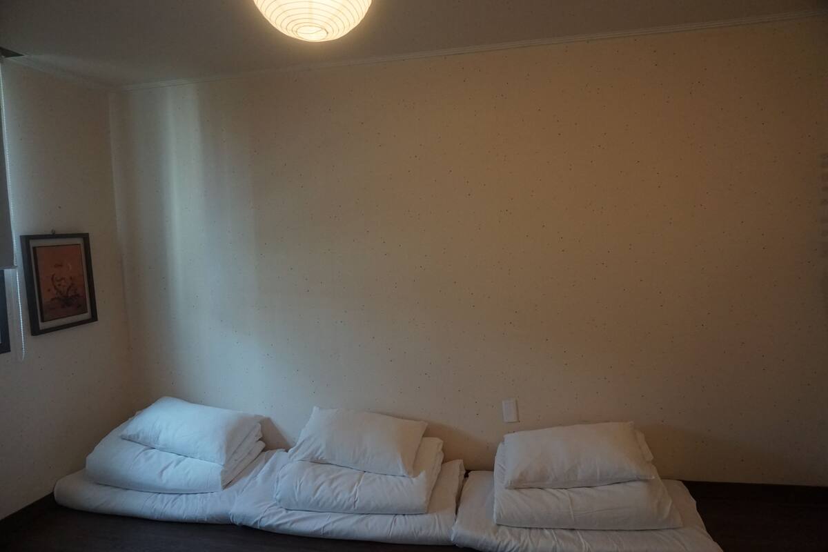 A room with a bed, a framed picture on the wall, and a light fixture.