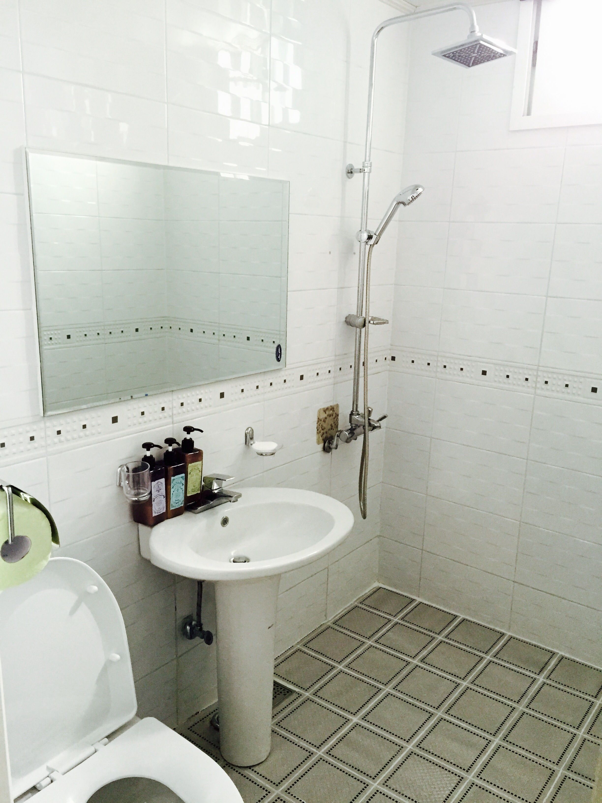 Un baño con lavamanos, espejo e inodoro blancos.