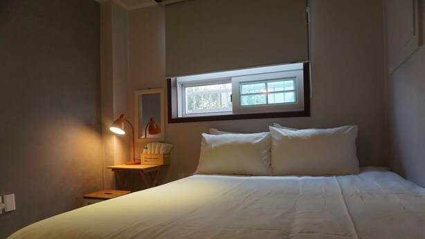 Una cama bien hecha con ropa de cama blanca en una habitación con una mesita y dos lámparas.