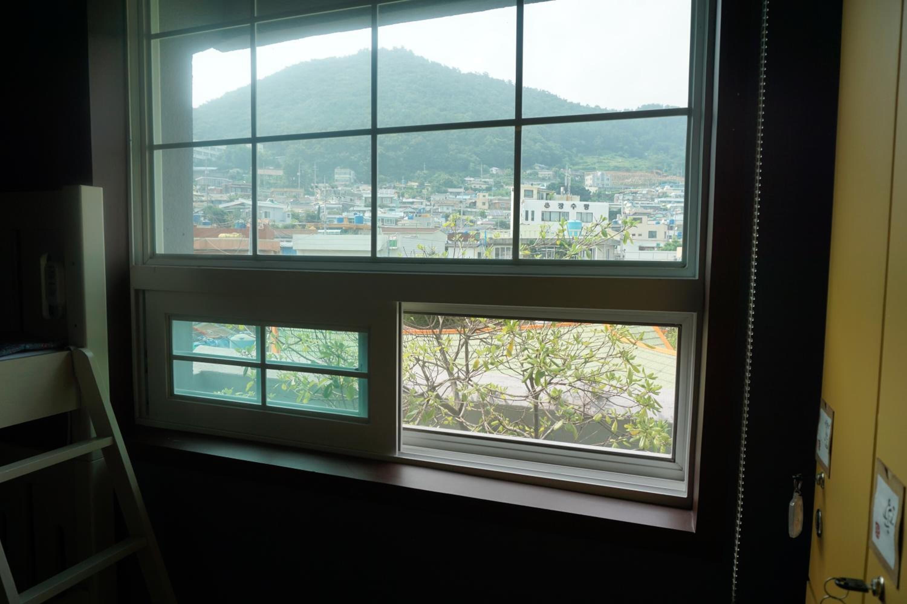 Una habitación con un amplio ventanal que ofrece vistas a un pueblo y colinas.
