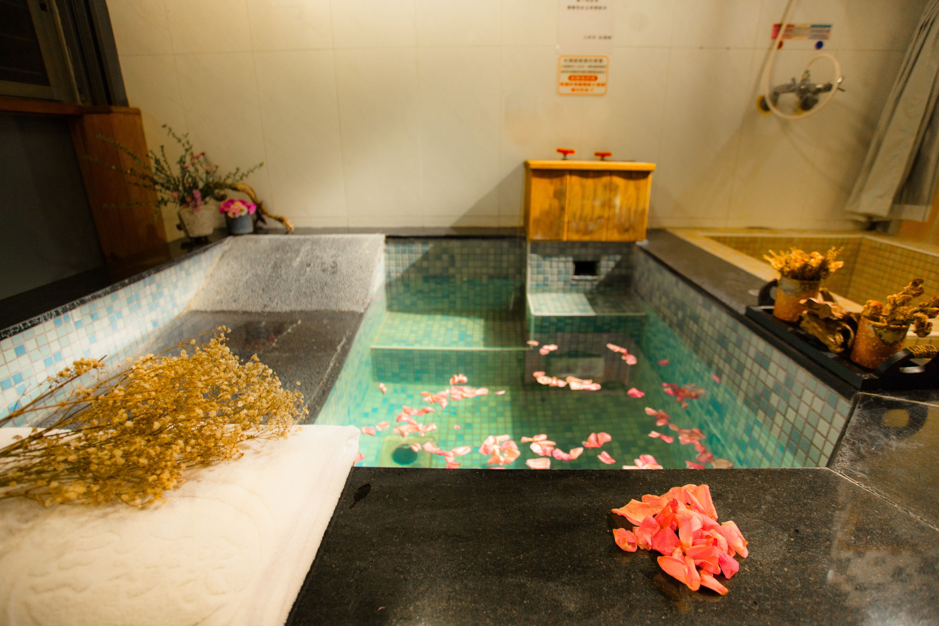 Ein Badezimmer mit Fliesenboden, einer Holzbank, einem Waschbecken und einer Duschkabine.
