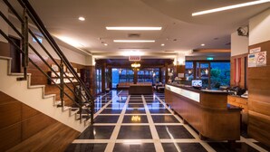 A hotel lobby with a check-in counter, a reception desk, a staircase, and a seating area. - WULAI SungLyu spring resort (New Taipei City)