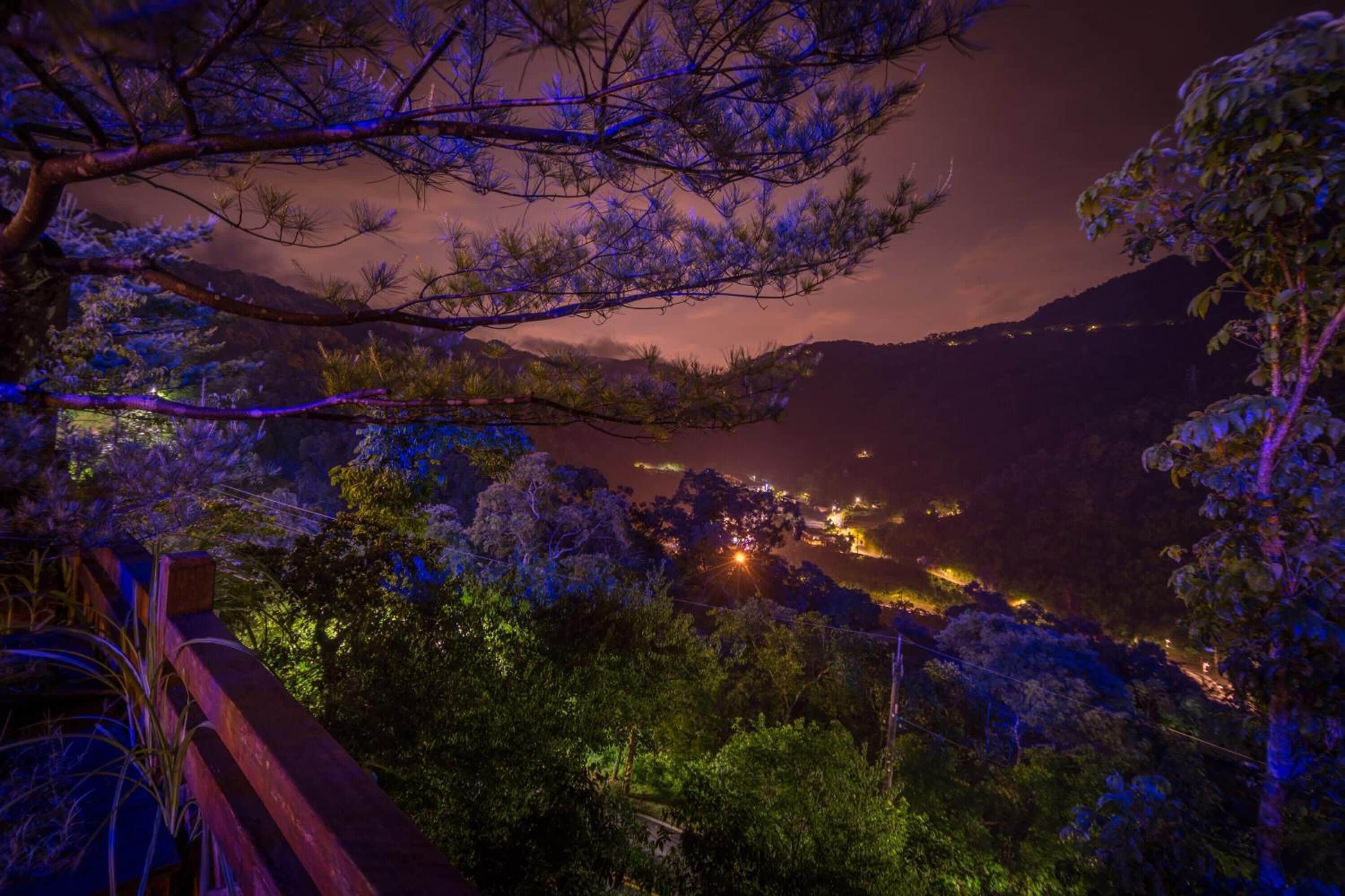 A nighttime view of a mountainous area with a lit-up town below.