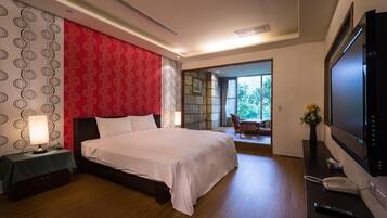 A modern hotel room with a large bed, a TV, a desk with a phone, and a view of the outdoors.
