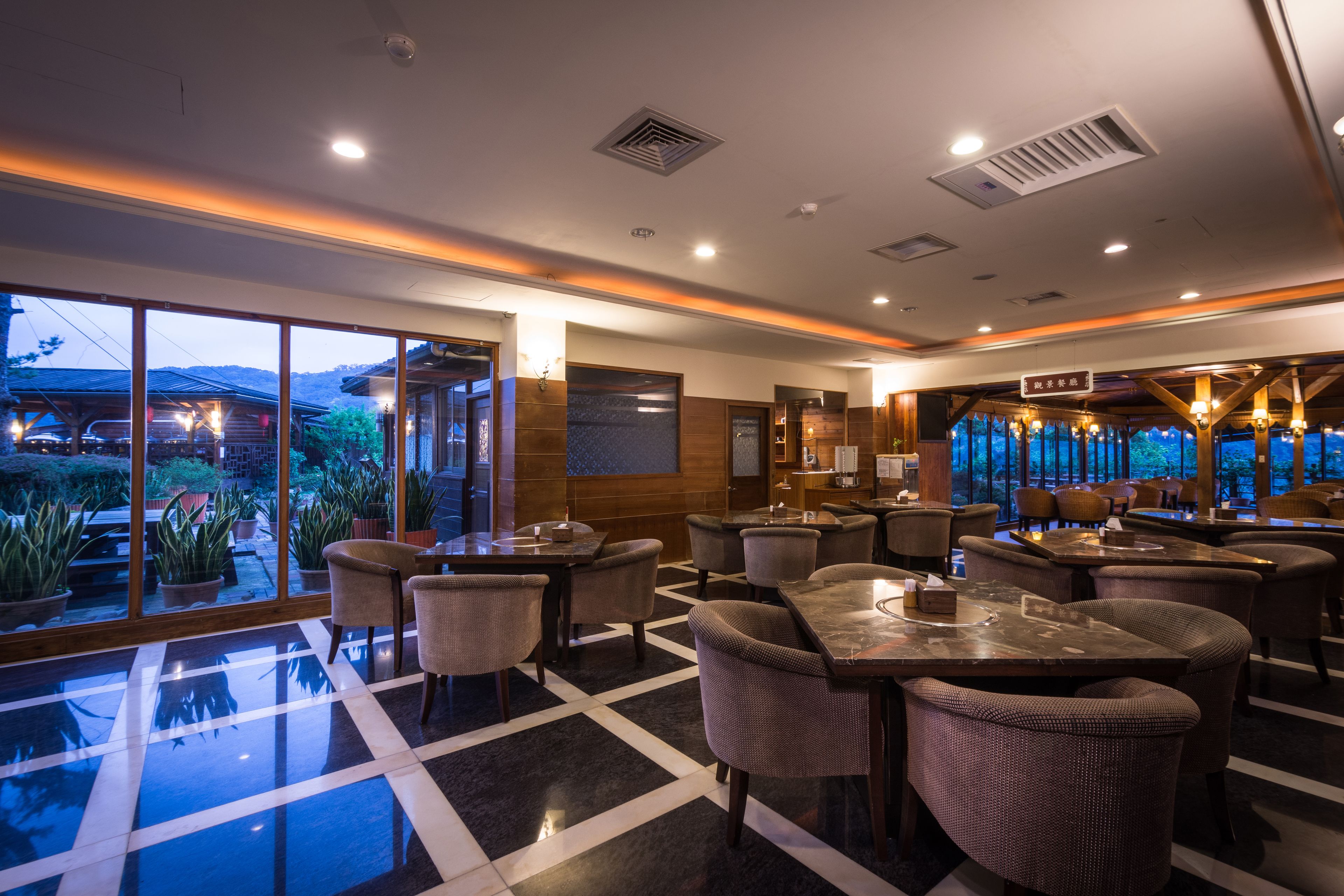 A spacious hotel lobby with large windows, a checkered floor, and a variety of seating arrangements.
