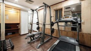Une salle de sport équipée d’un tapis de course, d’un banc de musculation et de divers appareils d’exercice.