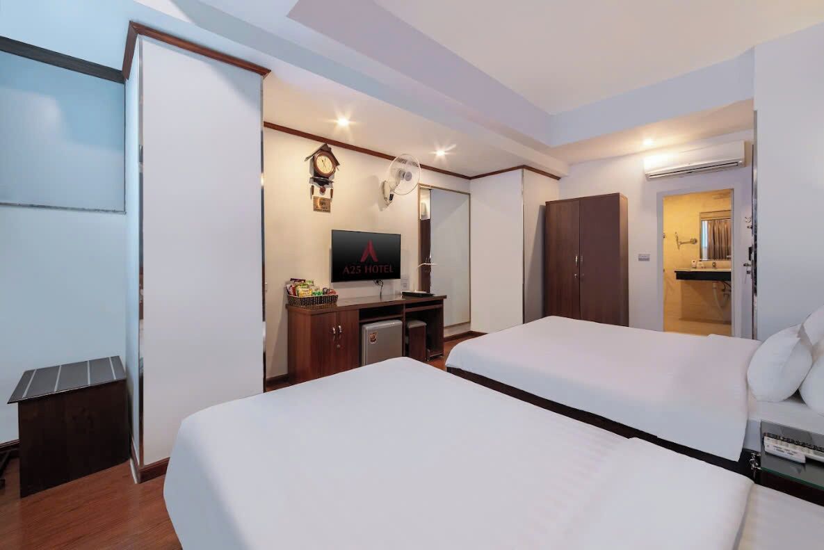 Een hotelkamer met twee bedden, een bureau met televisie, een klok en een minibar.