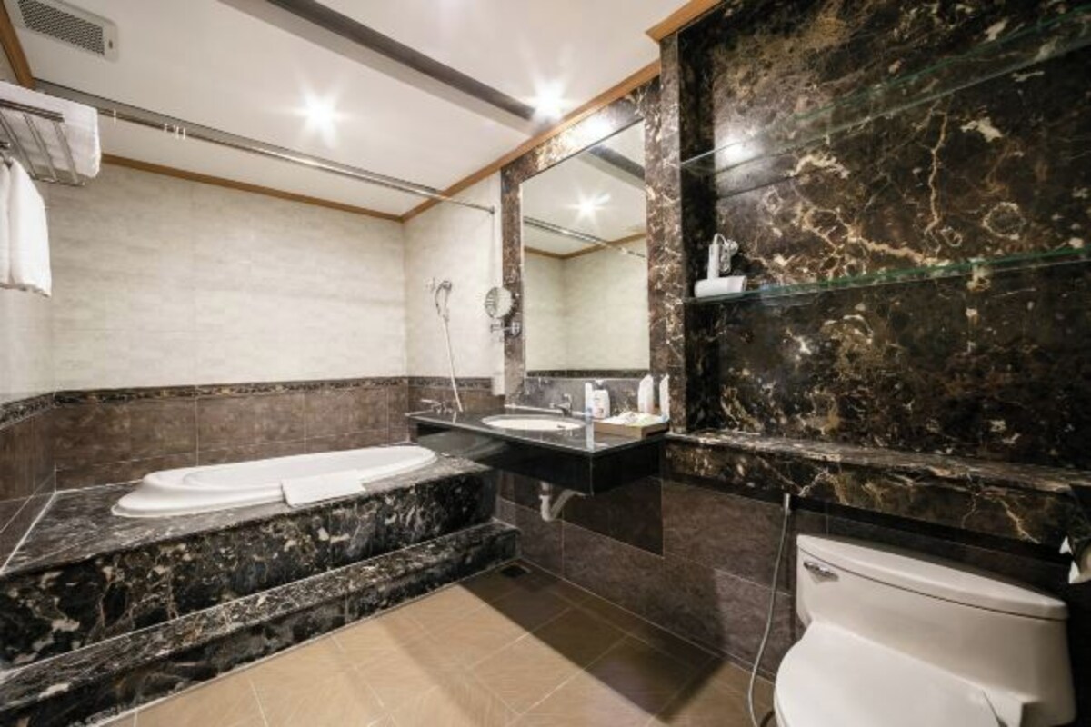 Un bagno moderno con una vasca, due lavandini, un water e pareti in marmo.