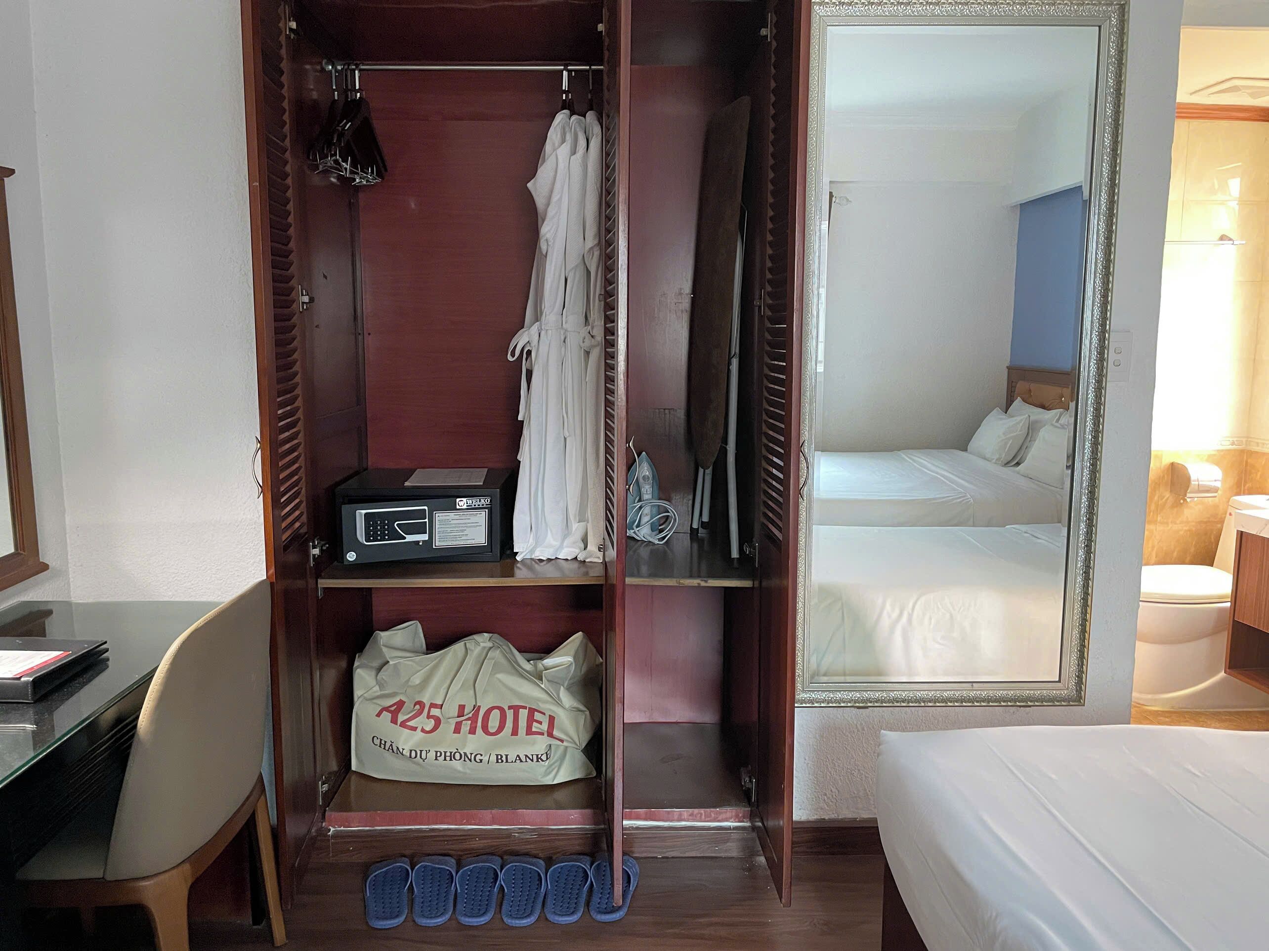 A hotel room with a bed, a desk, a wardrobe, and a mirror.