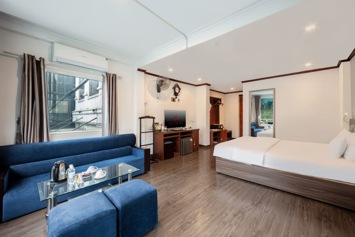 Une chambre d’hôtel avec un canapé, un lit, une télévision, une petite table et une vue sur l’extérieur.