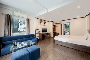 Une chambre d’hôtel avec un canapé, un lit, une télévision, une petite table et une vue sur l’extérieur.