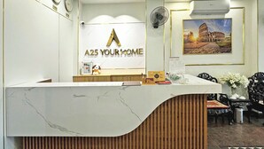 Un comptoir de réception d’hôtel avec un revêtement en marbre, des horloges, un tableau encadré représentant le Colisée et un jouet en peluche.