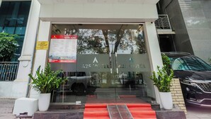 L’entrée d’un hôtel, avec une enseigne rouge indiquant « A25 – VOTRE ADRESSE », les coordonnées et une porte en verre.