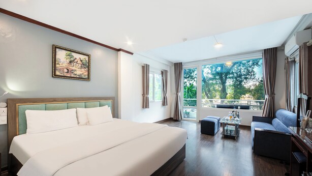Une chambre d’hôtel avec un grand lit, un canapé, une table basse et un tableau au mur.