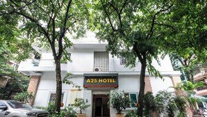 Außenansicht des Hotels A25 mit weißer Fassade, rotem Eingang und Pflanzen im Topf.