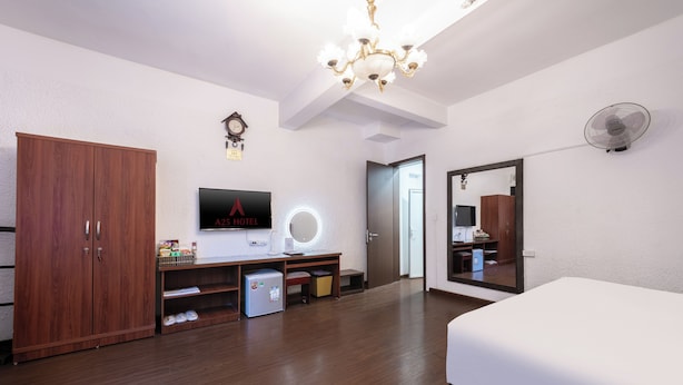 Ein Hotelzimmer mit einem Bett, einem Kleiderschrank, einem Schreibtisch mit Computer, einem Fernseher und einem Spiegel.