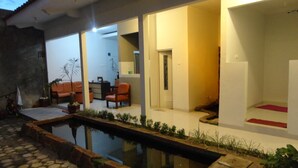 Une maison moderne dotée d’une piscine, d’un chemin en pierre et d’un espace patio aménagé avec des sièges.