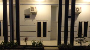 Une façade d’immeuble avec deux unités de climatisation, une porte et une petite fenêtre.