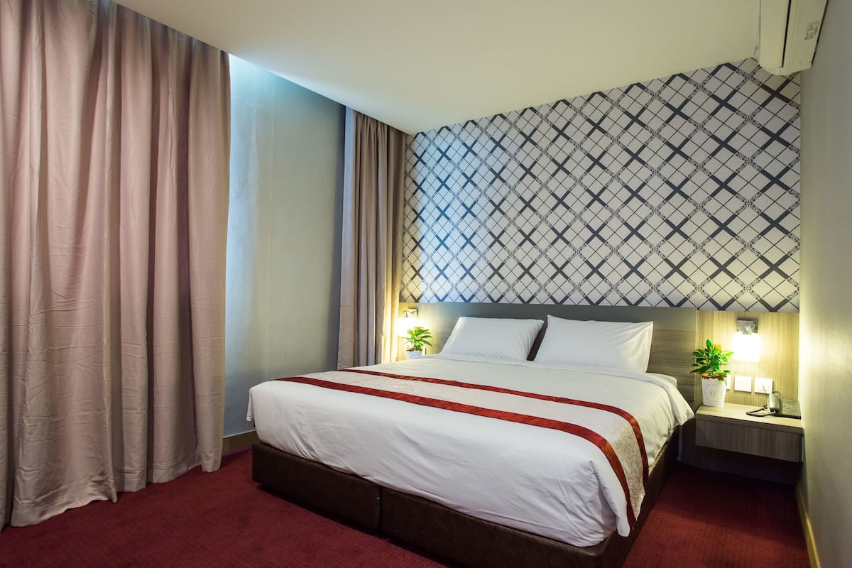 Et hotelværelse med en stor seng, et natbord med en lampe og en væg med mønster.