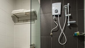 A bathroom with a toilet, a glass shower enclosure, and a wall-mounted heater. - LS Hotel (Masai)