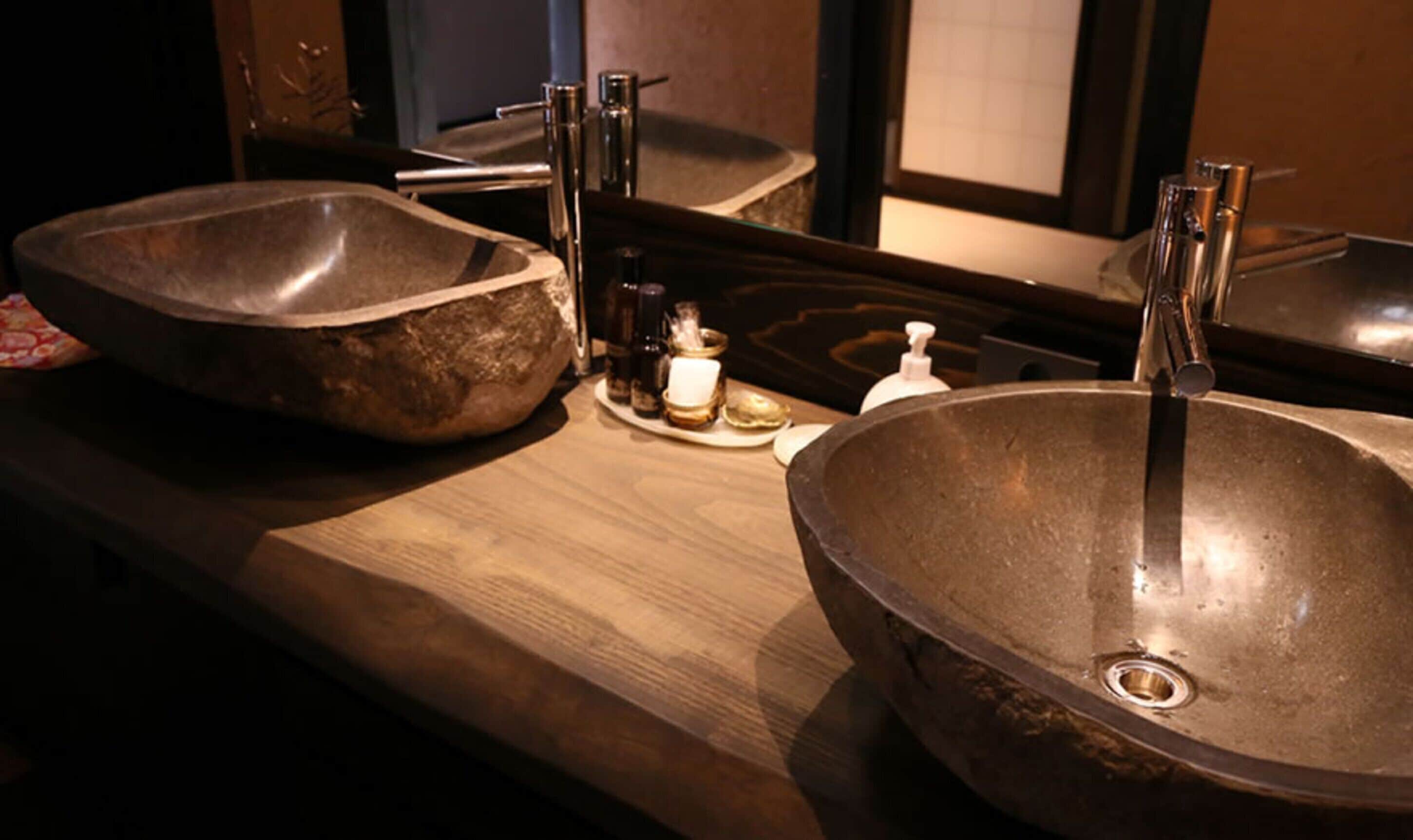A bathroom with two large, round, metallic sinks and a wooden countertop.