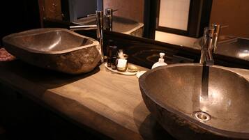 A bathroom with two large, round, metallic sinks and a wooden countertop.