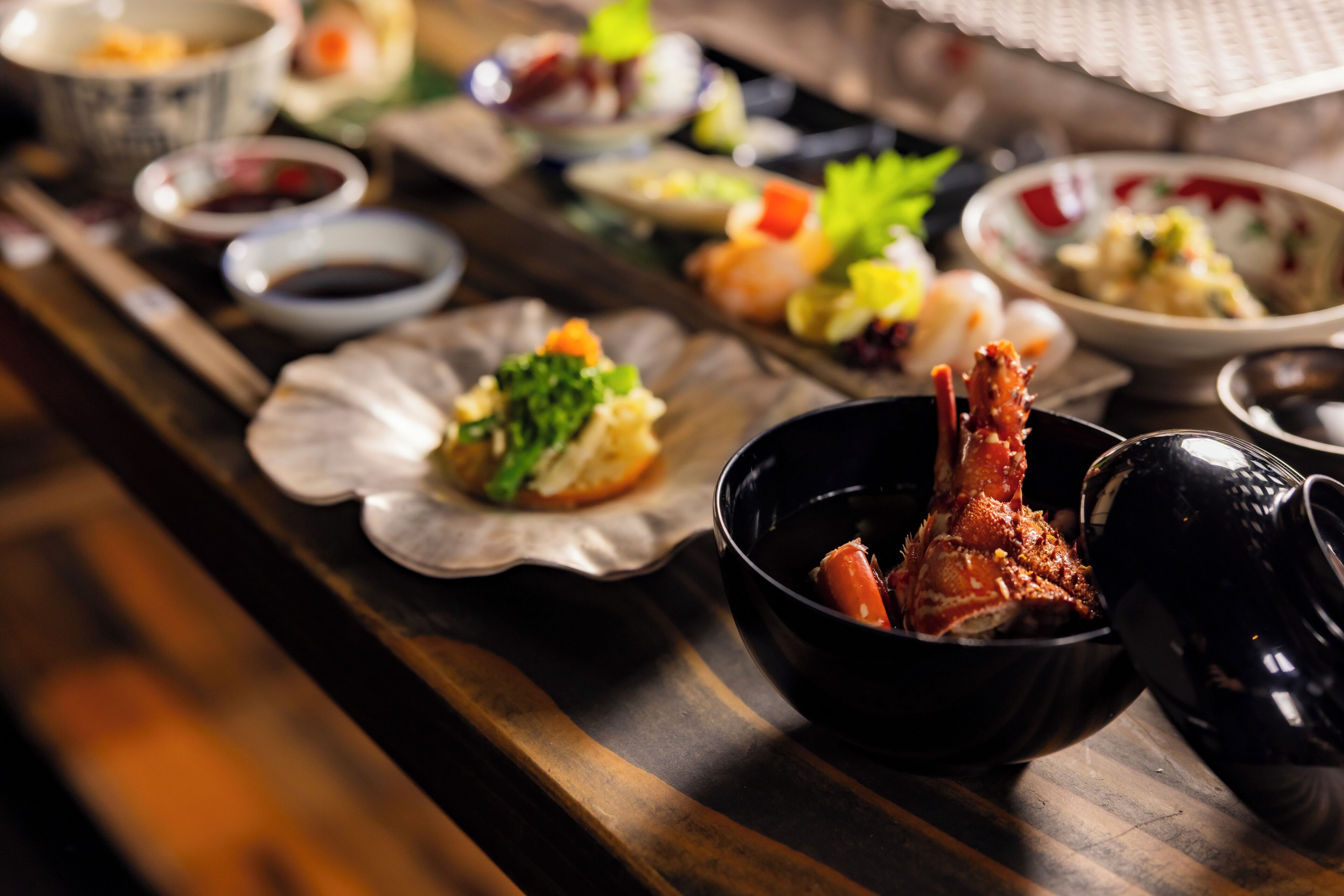 A variety of dishes on a wooden table, including seafood and vegetables.