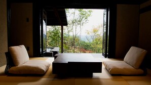 Una habitación tradicional japonesa con suelo de tatami, una mesa baja y dos zonas de estar acolchadas.