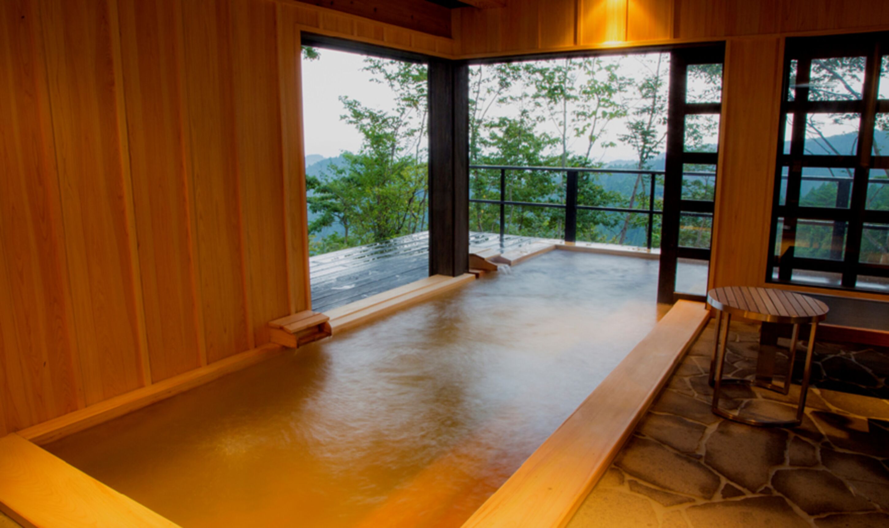 A wooden interior with a stone floor, a bench, and a table.