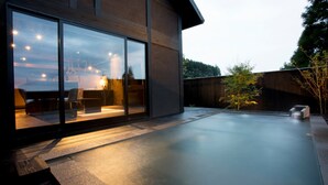 Una casa moderna con un amplio ventanal, un patio de concreto y una cerca de madera.