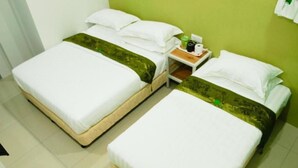 A hotel room with two single beds, a nightstand with toiletries, and a green wall. - Green Hotel (Sungai Besar)