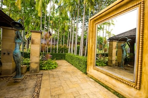 A garden pathway with a large mirror and statues.
