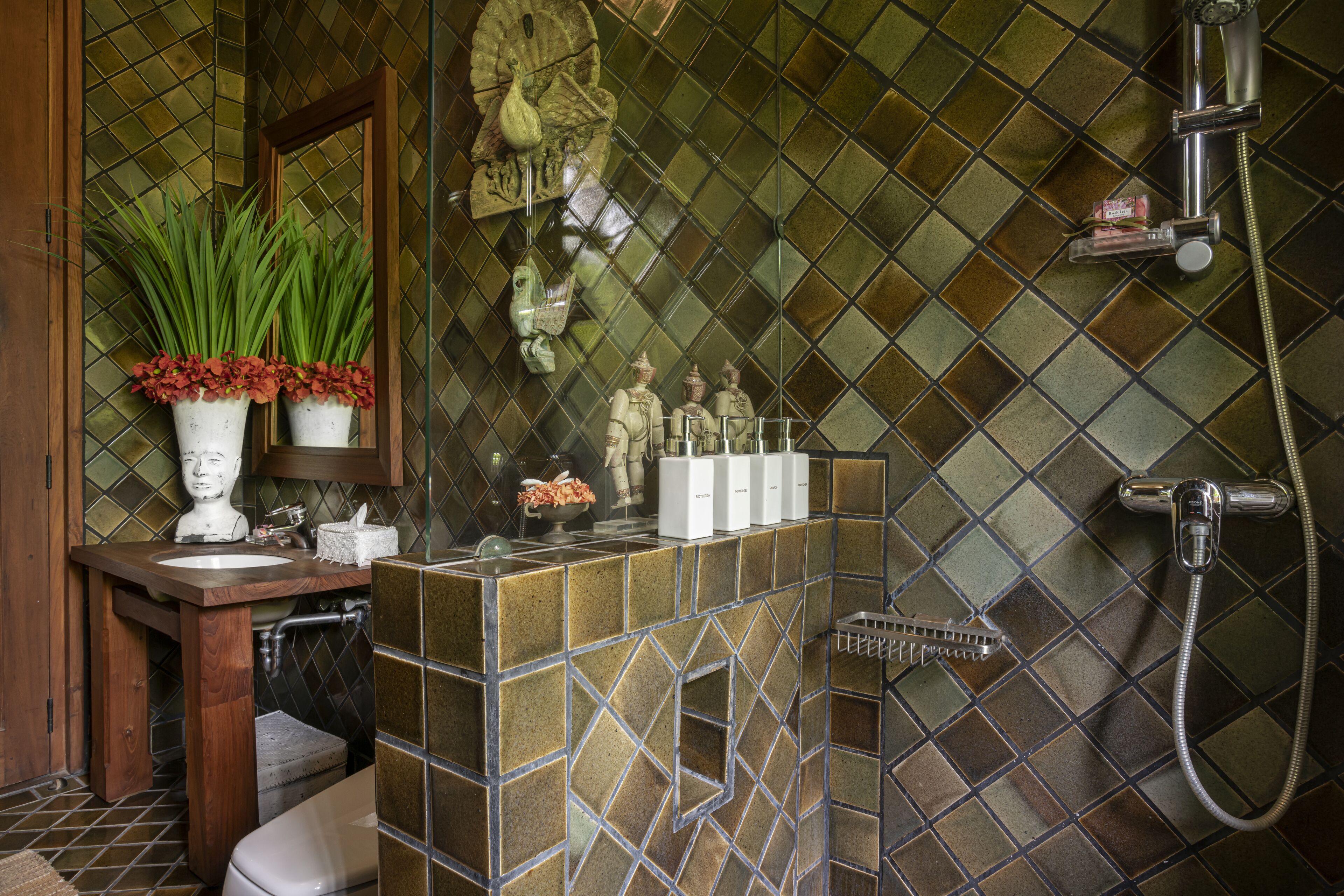 A bathroom with a mosaic tile wall, a wooden vanity, a toilet, and a shower area.