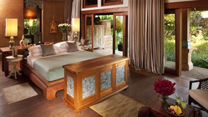 A spacious bedroom with a large bed, wooden furniture, and a view of the garden. - Howie's Homestay (Mae Rim)