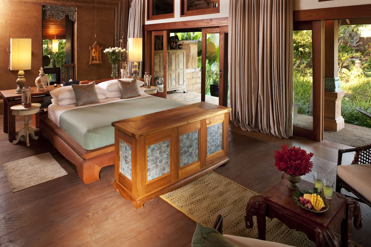 A spacious bedroom with a large bed, wooden furniture, and a view of the garden.