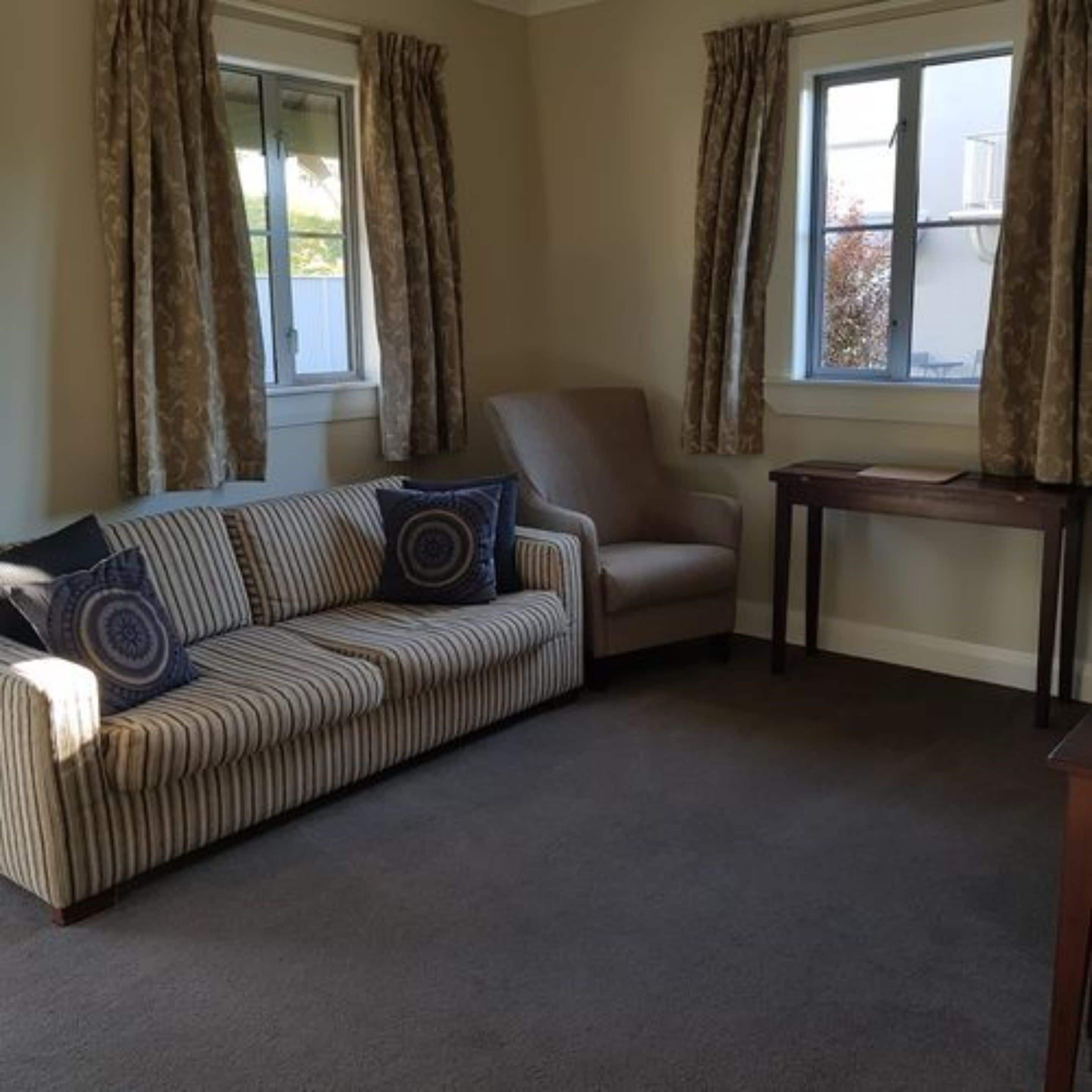 A living room with a striped sofa, a chair, and a small table.