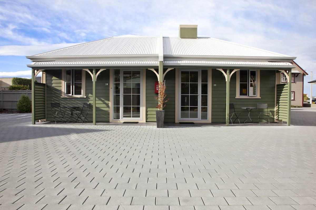 A green building with a flat roof and a covered porch area.